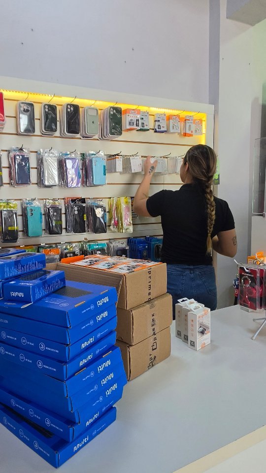 Interior da loja com parede de capinhas e caixas de produtos